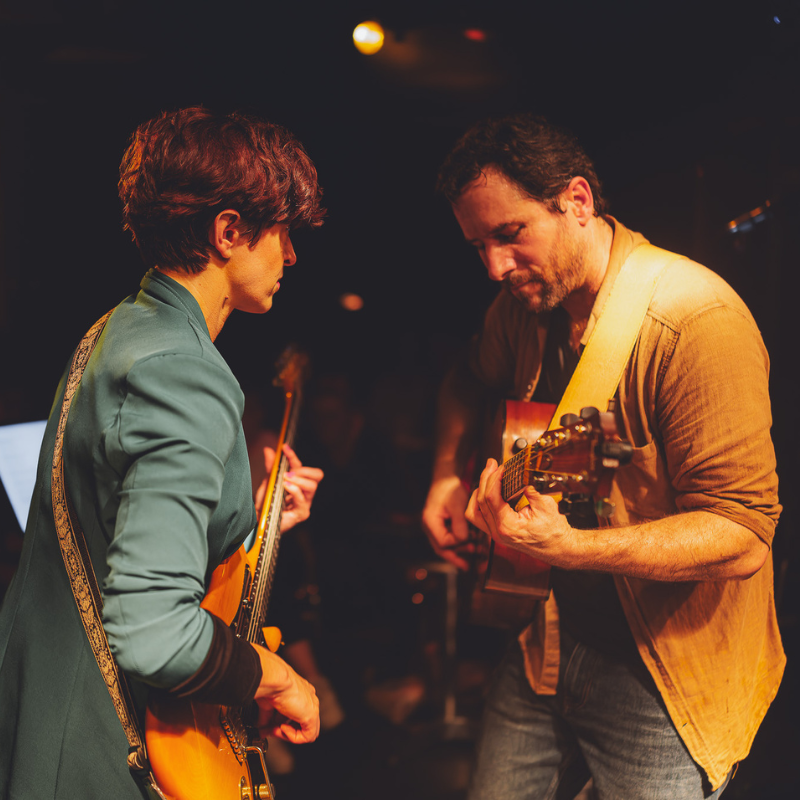 Tamara à la basse et Olivier à la guitare acoustique jouent ensemble sur scène, Ol’d Tam, duo Jukebox