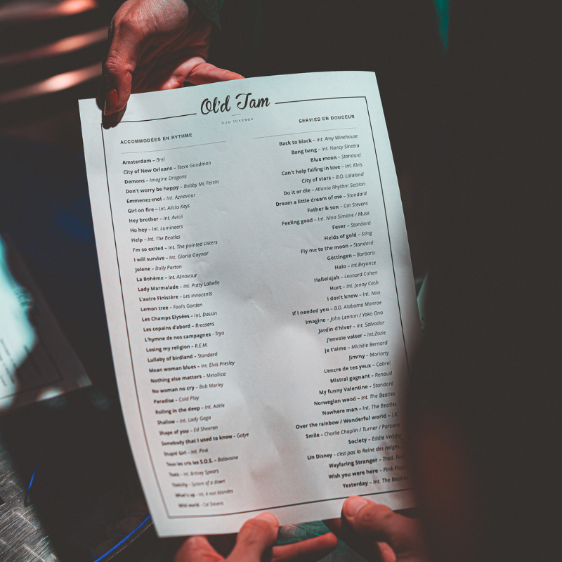 Menu des chansons d’Ol’d Tam, duo Jukebox, tenu en main avec une liste de plus de 80 titres
