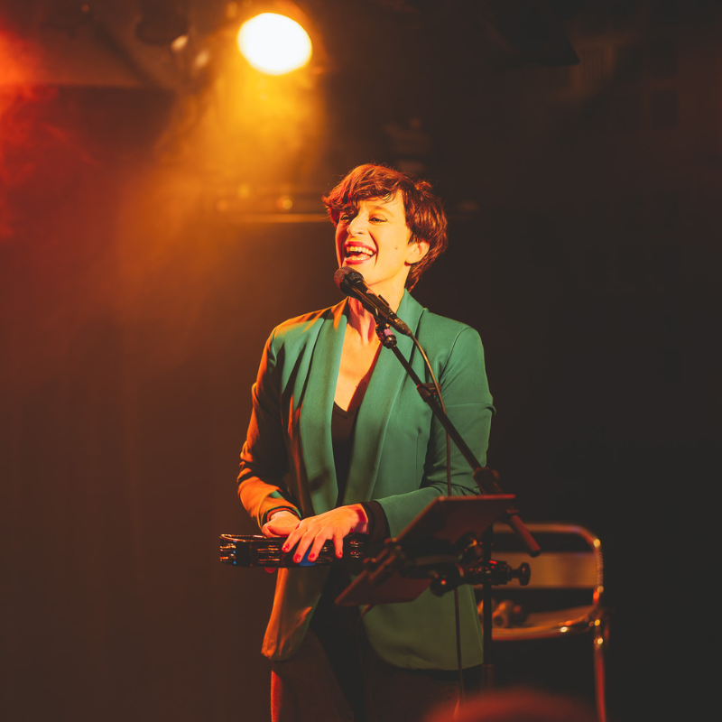 Tamara, chanteuse du duo Ol’d Tam, souriant en chantant avec un tambourin à la main