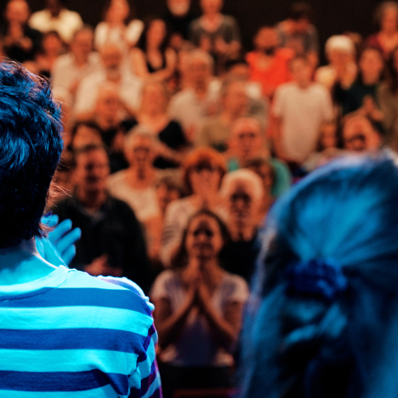 Vue depuis la scène de la Chorale Pirate sur un public debout et applaudissant