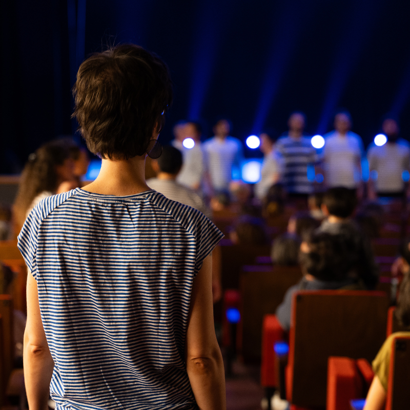 Une choriste observe la Chorale Pirate en concert sur scène