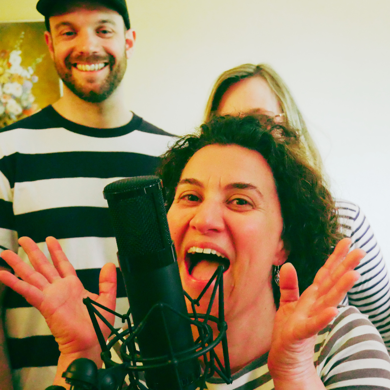 Une chanteuse de la Chorale Pirate interprétant avec énergie devant un micro, entourée de choristes souriants.
