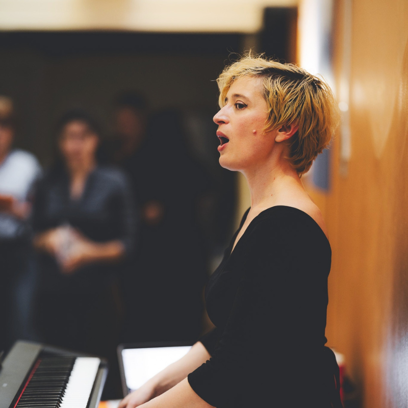 La cheffe de chœur de la Chorale Pirate, Tamara Dannreuther, joue et chante au piano.