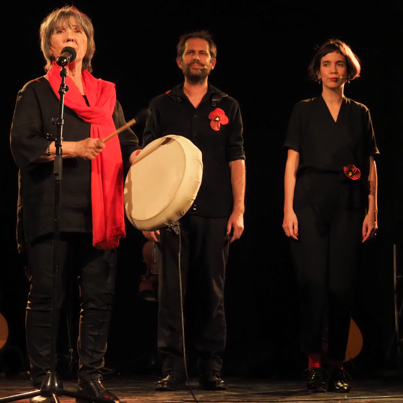 Martine Scozzesi joue du tambour sur la chanson "Pleure ma terre", accompagnée au chant par Manon Maurin et Norbert Gautier, lors du spectacle "Chansons & Coquelicots", hommage à Anne Sylvestre.