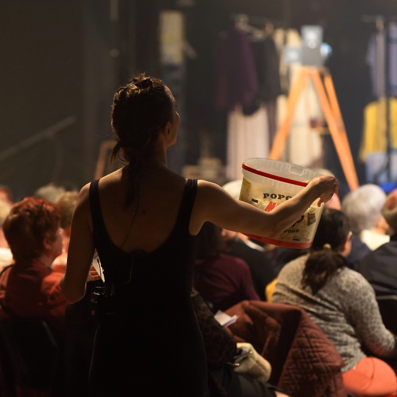 Interprète distribuant du popcorn au public pendant le spectacle Splendeur & Décadence