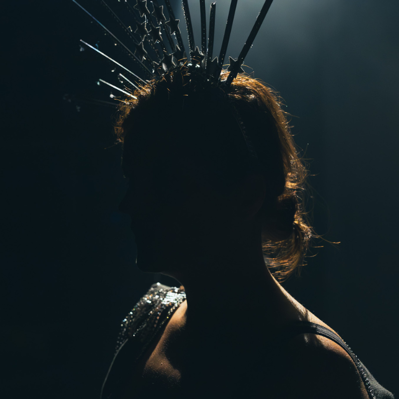Profil d’une interprète coiffée d’une couronne étoilée, éclairée en clair-obscur dans Splendeur & Décadence