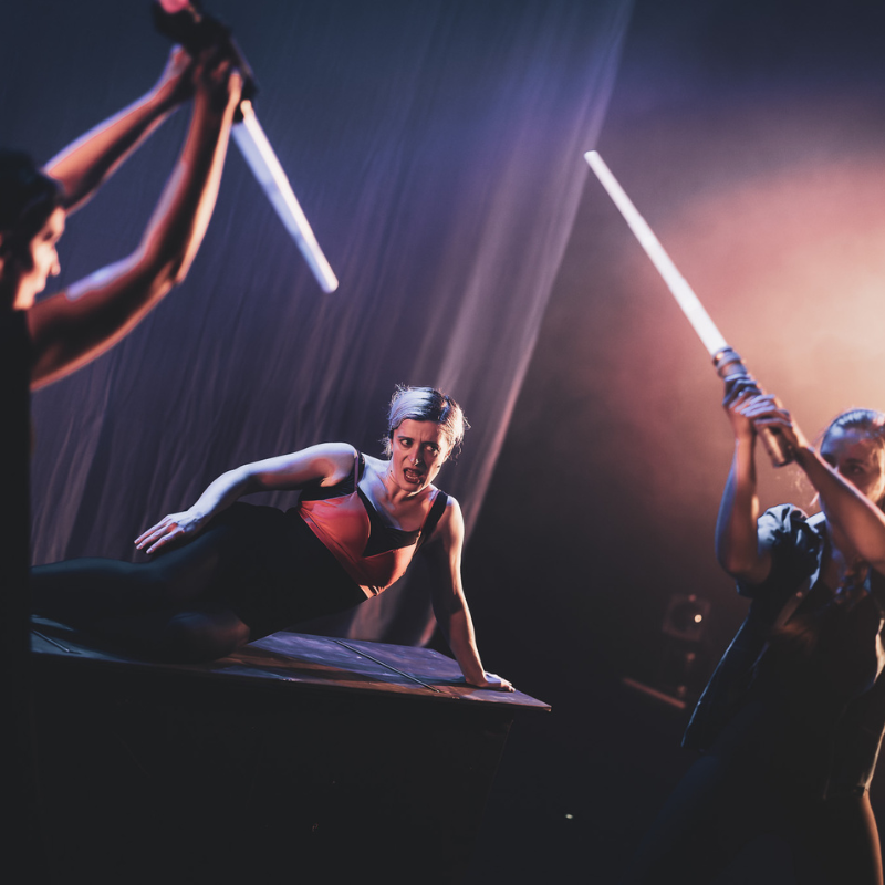 Interprètes en combat chorégraphié avec sabres lumineux, une actrice au sol dans Splendeur & Décadence