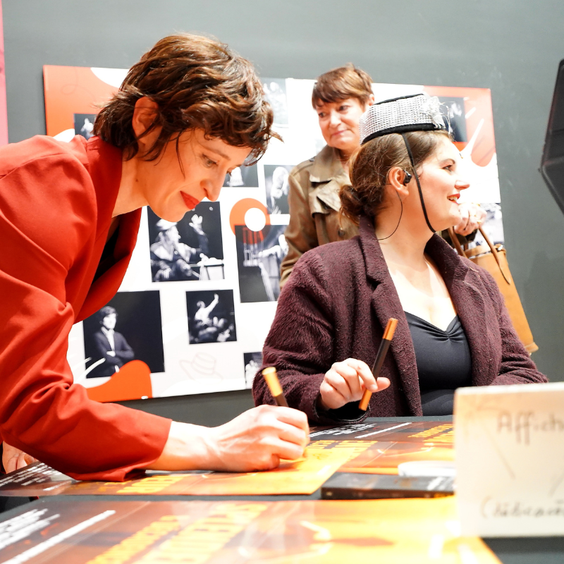 Deux interprètes de Splendeur & Décadence signant des affiches après le spectacle