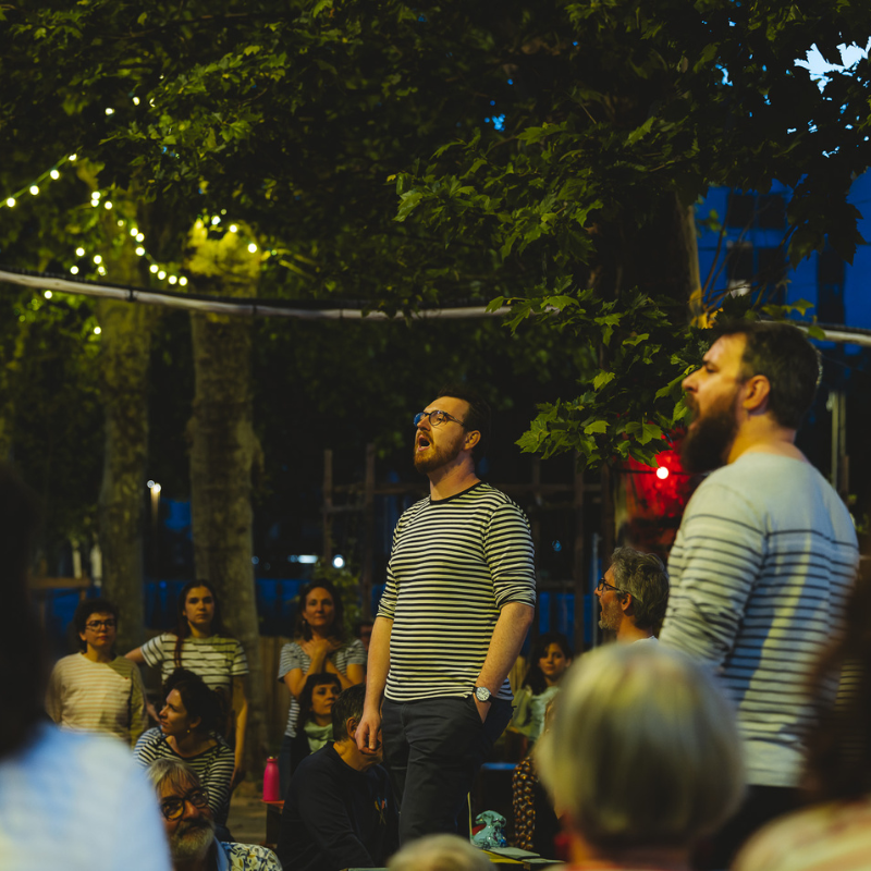 Chorale Pirate chantant de nuit dans un parc illuminé de guirlandes à La Filature Villeurbanne