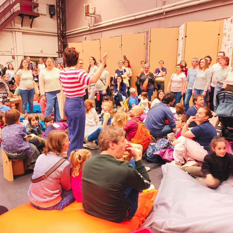 Chorale Pirate animant un concert immersif entourée d’enfants et de familles assises au sol