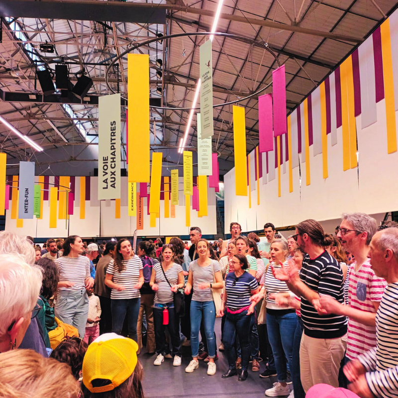Chorale Pirate chantant en cercle au milieu d’un hall décoré de bannières colorées