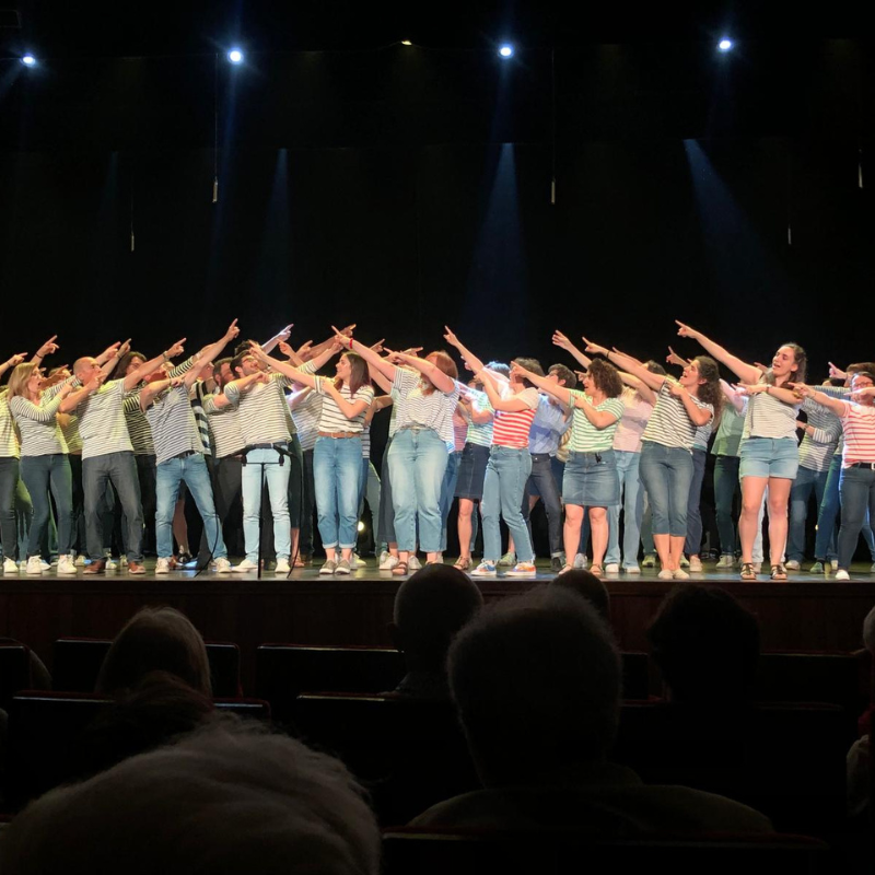 Chorale Pirate sur scène réalisant une chorégraphie avec les bras tendus en groupe